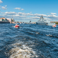 view from a tourist ship of warships docked on the Neva River against the background of a blue cloudy sky