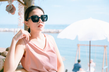 Woman enjoying beach relaxing joyful in summer by tropical blue water. model on travel wearing sun glasses.