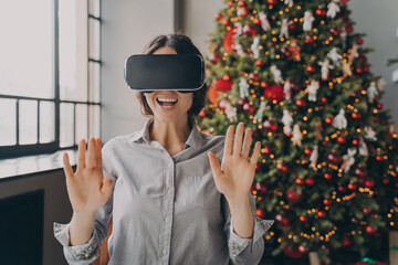 Impressed europian lady using VR googles while spending Christmas at home