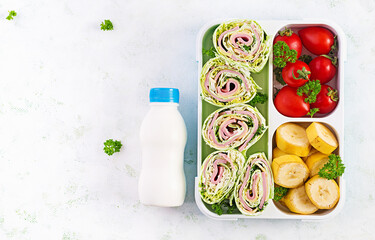 School lunchbox. Healthy lunch box with tortilla wraps, tomatoes, banana and yogurt. Top view, flat...