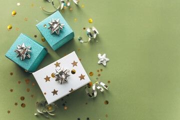 Gift white and green boxes with a tinsel and confetti on a green background. The concept of a gift, a new year, a festive background. Flat lay, top view