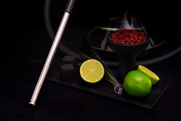 Hookah bowl with tobacco citrus fruits on dark background