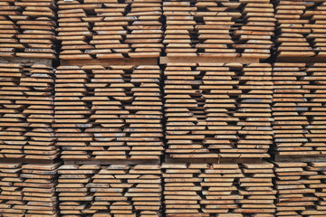 Unedged board of soft wood stacked on production site. Selective focus.
