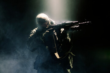 A member of a special purpose unit. Russian special forces soldiers with submachine gun in clouds of smoke on a black background with colored illumination.