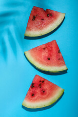 Delicious ripe watermelon and tropical leaf shadow on light blue background, flat lay