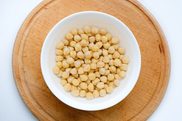 Fresh raw organic chickpeas soaked in water on a white table on a wooden tray. The benefits of legumes. Vegan nutritive proteinaceous food. Taking care of your health. Empty space. 
