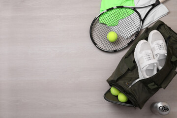 Sports bag and tennis equipment on wooden background, flat lay. Space for text
