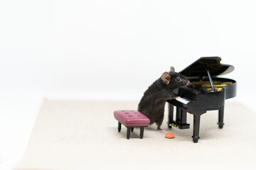 A gray mouse next to the piano. Doll furniture