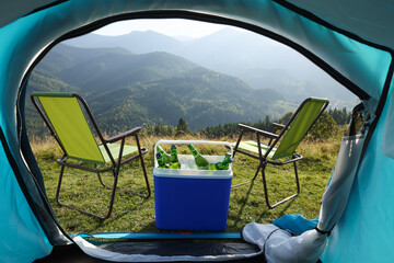 Chairs and cool box with bottles of beer in mountains, view from tent © New Africa