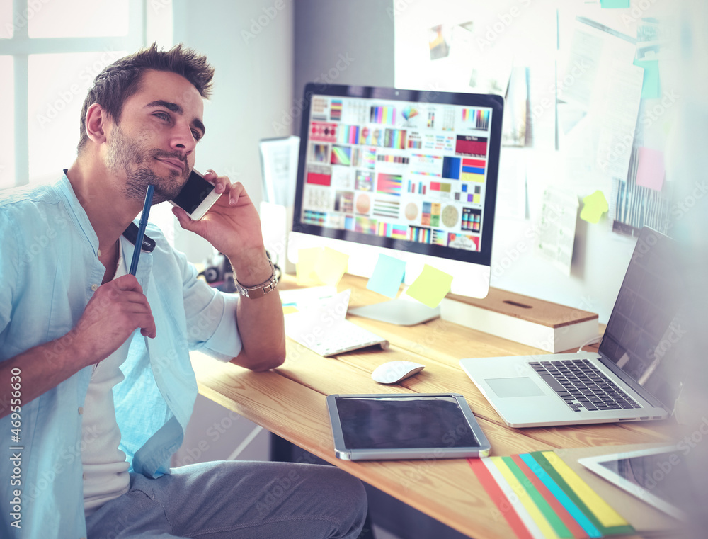 Poster portrait of young designer sitting at graphic studio in front of laptop and computer while working o