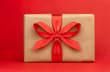 Photo sur Plexiglas Doux monstres Boîte cadeau emballée avec ruban rouge pour une célébration sur fond rouge