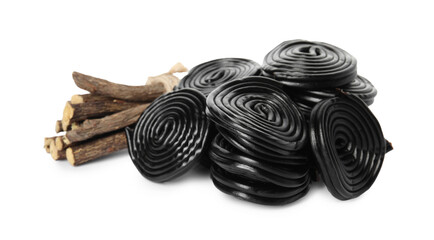 Tasty black candies and dried sticks of liquorice root on white background