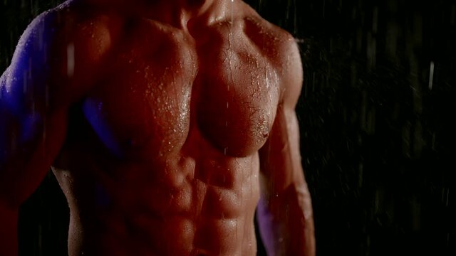 sexy male torso in rain or shower, closeup view of tensed muscles on abdomen, six pack
