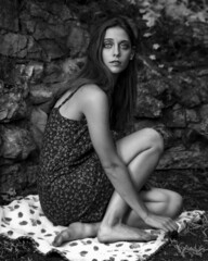 Naklejka premium Black and white image of a young woman in flower print dress, exploring a woodland garden.