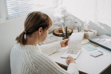 2022 goals, New year resolution. Woman in white sweater writing Text 2022 goals in open notepad on...