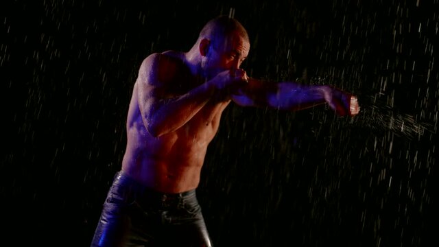 professional boxer or kickboxer is fighting with imaginary enemy in rain