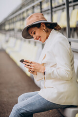 Young woman sitting on arena seats and talking on the phone