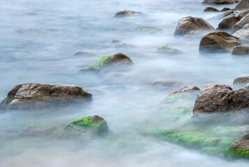 Sea stones in the water of the Mediterranean Sea. Water creates fog due to long exposure.