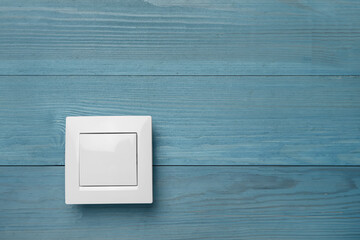 White light switch on turquoise wooden background. Space for text