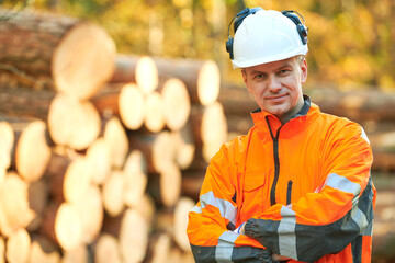 Forestry worker in protective workwear in front of wood lumber cut tree