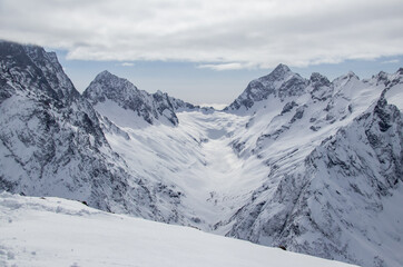 Fototapeta na wymiar Snowy Mountains peaks in the clouds blue sky Caucasus