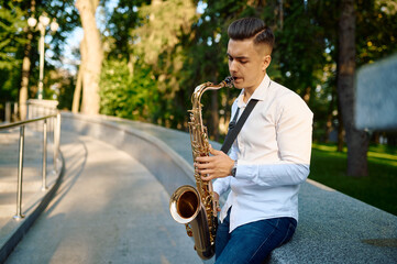 Young saxophonist plays the saxophone in park