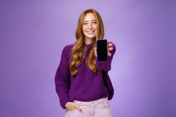 Girl shows smartphone screen at camera to ask opinion of friend smiling broadly with optimistic and...