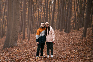 Young couple in the autumn forest. Male and female in relationship are having great time in outdoor