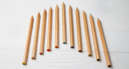 Multi-colored pencils on a white wooden background. Drawing set. School accessories. Banner