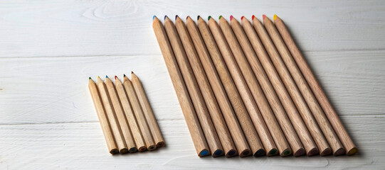 Multi-colored pencils on a white wooden background. Drawing set. School accessories. Banner
