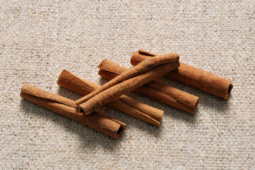 Five cinnamon sticks on a linen fabric background