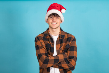 young man with santa claus hat isolated on blue colored background