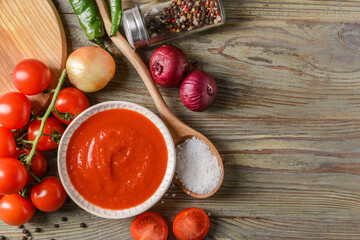 Bowl with organic tomato sauce and ingredients on table