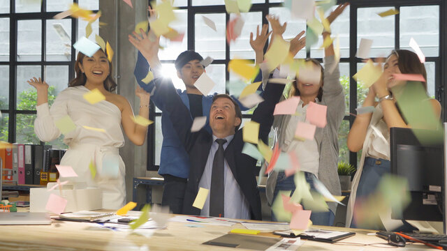 A successful group of multi ethnic business team employee have a meeting, having fun, throwing sticky notes in the meeting room office. business analysis. People lifestyle. Celebration. Cooperation.