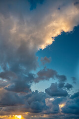 Fototapeta na wymiar Rain clouds and the setting sun against the blue sky.