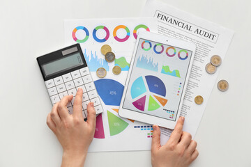 Woman with calculator, tablet computer and charts on white background