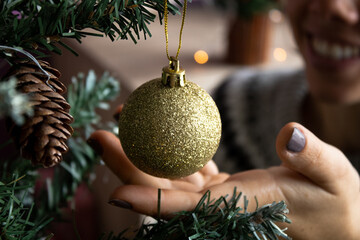Mano decorando arbol de navidad con bola dorada