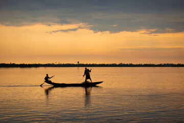 Naklejka premium A man rowing on river niger in Africa trying to catch fish