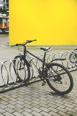Fototapeta na wymiar A bicycle in the parking lot against the background of a yellow wall. Courier's bike led parked