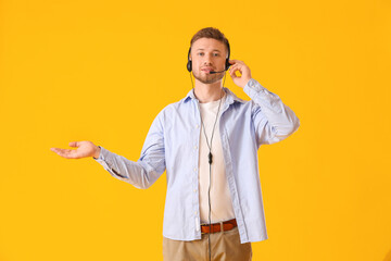 Handsome consultant of call center in headset on yellow background