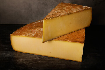 Comte cheese on dark background. Aged french cheese made from unpasteurized cow's milk