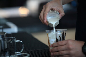 preparing fresh coffee of male hands pouring milk and preparing fresh cappuccino, coffee artist and preparation concept
