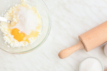 Bowl with ingredients for delicious dumplings and rolling-pin on light background