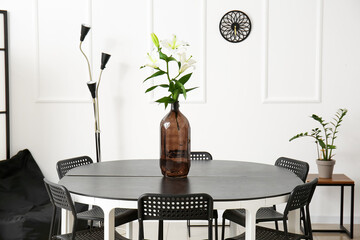 Stylish interior with round table and chairs near white wall