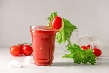 Glass of bloody mary with celery and tomatoes on table