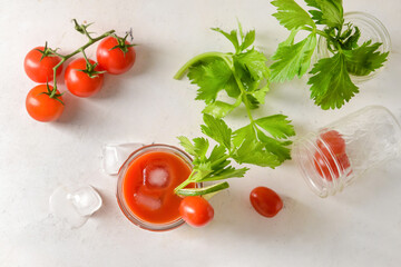 Glass of bloody mary with celery and tomatoes on light background