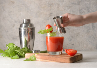 Woman making bloody mary cocktail at table