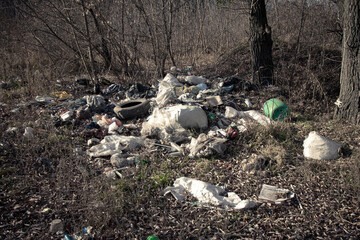 Obraz premium A large pile of rubbish in the forest near the road. Illegal garbage disposal. Forest pollution with human waste