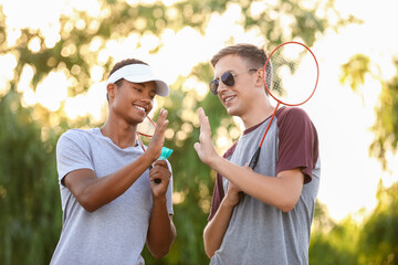 Fototapeta premium Male badminton players giving each other high-five in park