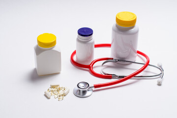 The concept of treatment during illness. White jar with goodies and a stethoscope on a light background. View from above.